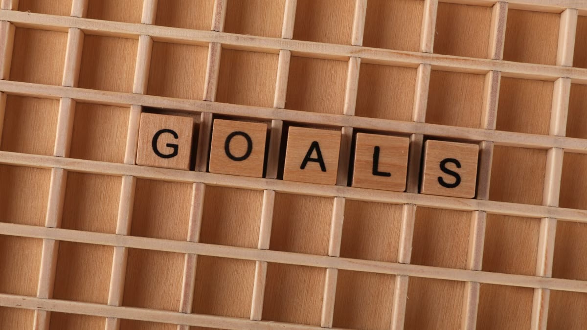Wooden alphabet tiles spelling 'GOALS' on a grid background, symbolizing aspirations.